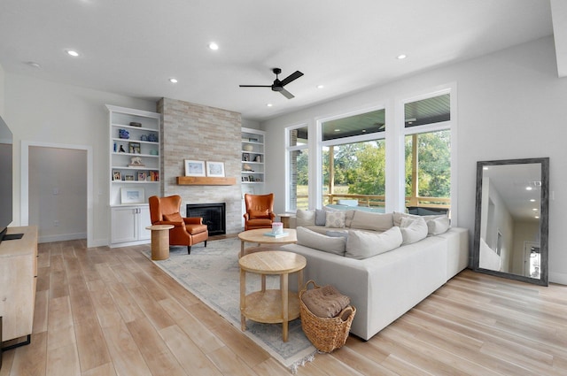 living area with light wood-style flooring, ceiling fan, a large fireplace, and recessed lighting