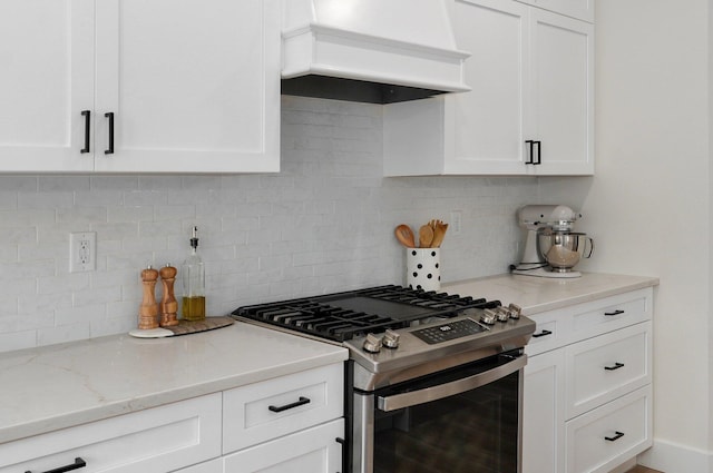 kitchen featuring stainless steel gas stove, custom range hood, tasteful backsplash, and white cabinets