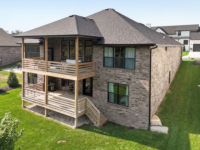 rear view of house with brick siding, a shingled roof, a yard, a balcony, and a wooden deck