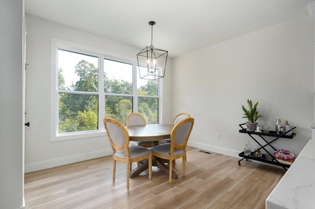 dining area with a chandelier, baseboards, and light wood finished floors