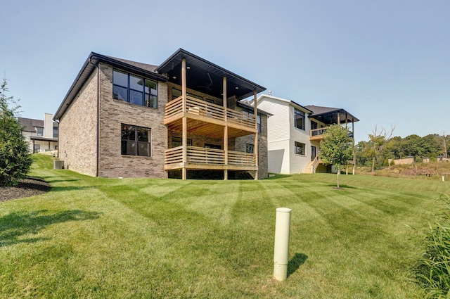 rear view of property with a balcony, brick siding, and a lawn