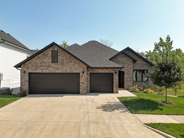 view of front of house with brick siding, driveway, an attached garage, a front lawn, and a shingled roof