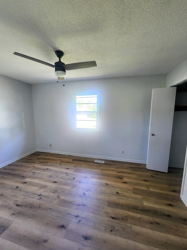 unfurnished room with wood finished floors, a textured ceiling, baseboards, and ceiling fan