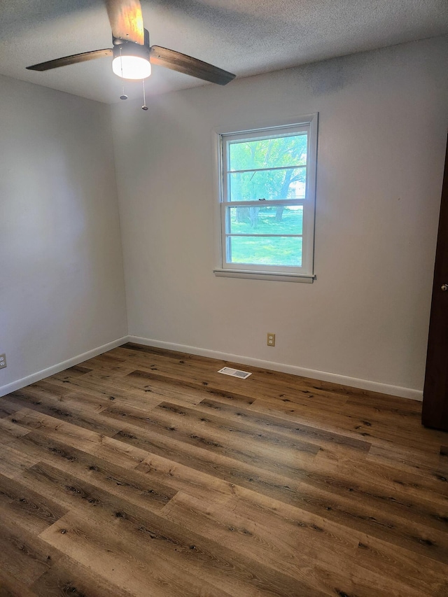 unfurnished room featuring dark wood-style flooring, ceiling fan, baseboards, and a textured ceiling