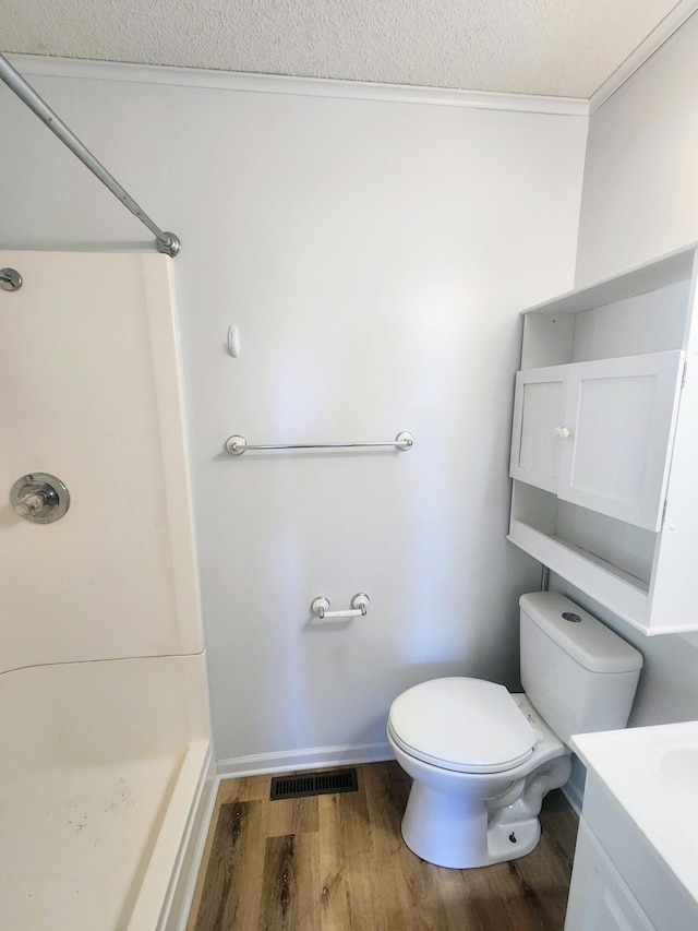 bathroom featuring a shower, wood finished floors, toilet, and vanity