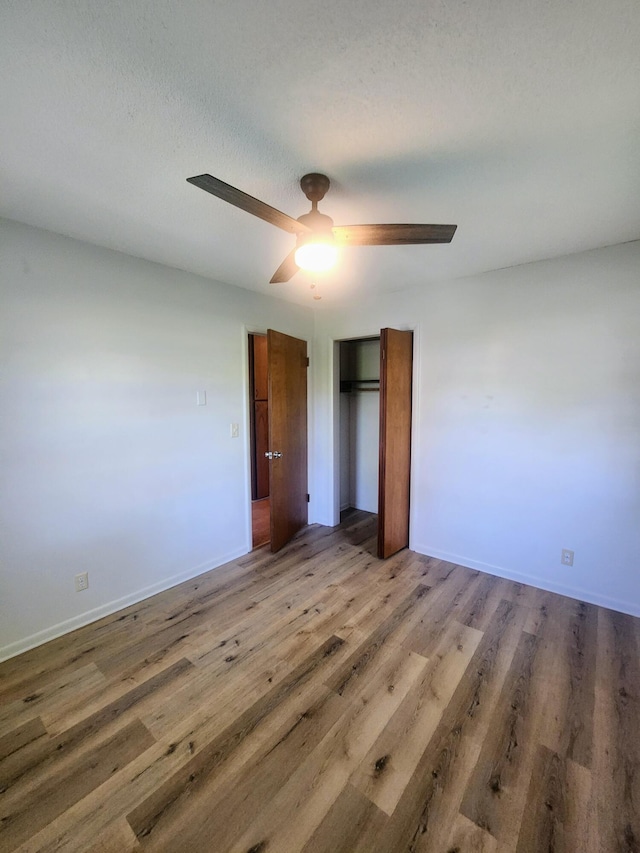 unfurnished bedroom with a closet, wood finished floors, ceiling fan, and baseboards