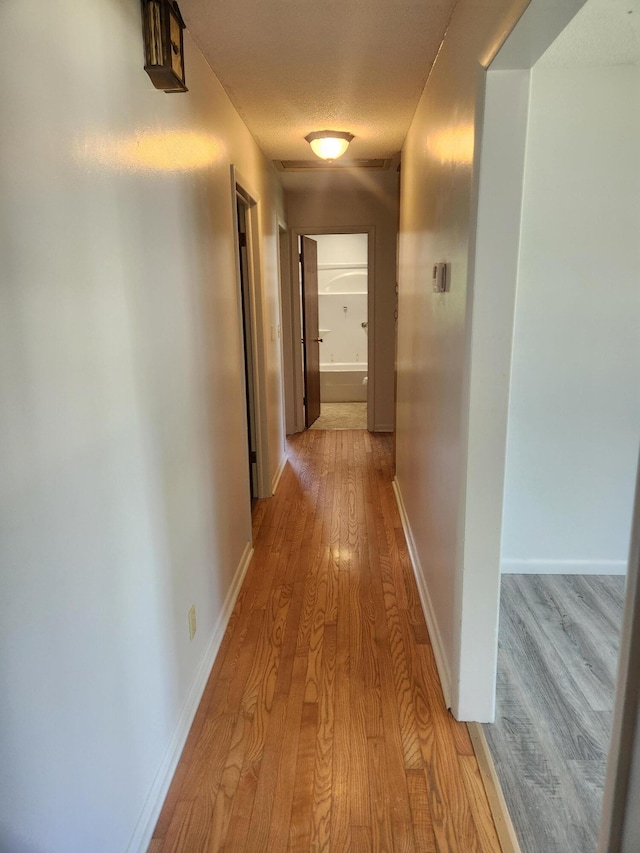 corridor with light wood finished floors and baseboards