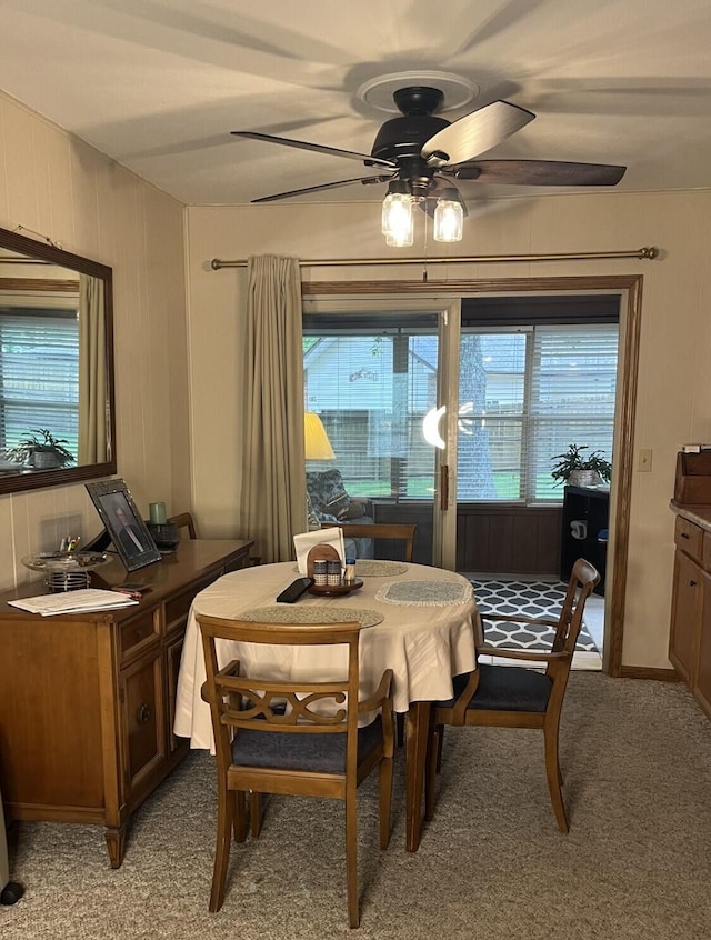 dining area with a ceiling fan and light colored carpet