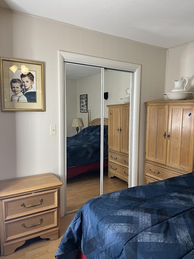 bedroom with wood finished floors, a decorative wall, and a closet