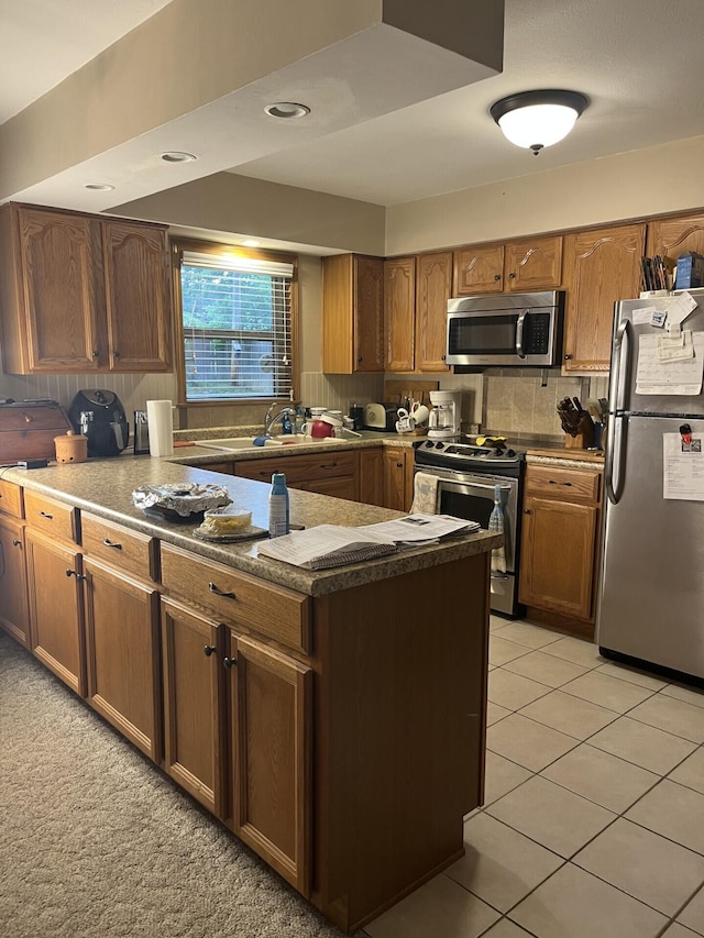 kitchen featuring appliances with stainless steel finishes, a sink, tasteful backsplash, light tile patterned floors, and brown cabinets