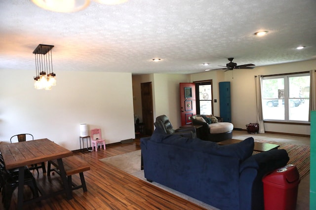 living area with a ceiling fan, wood finished floors, baseboards, a textured ceiling, and recessed lighting