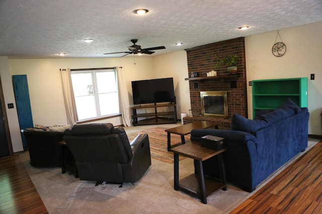 living area featuring a textured ceiling, wood finished floors, a ceiling fan, a fireplace, and recessed lighting