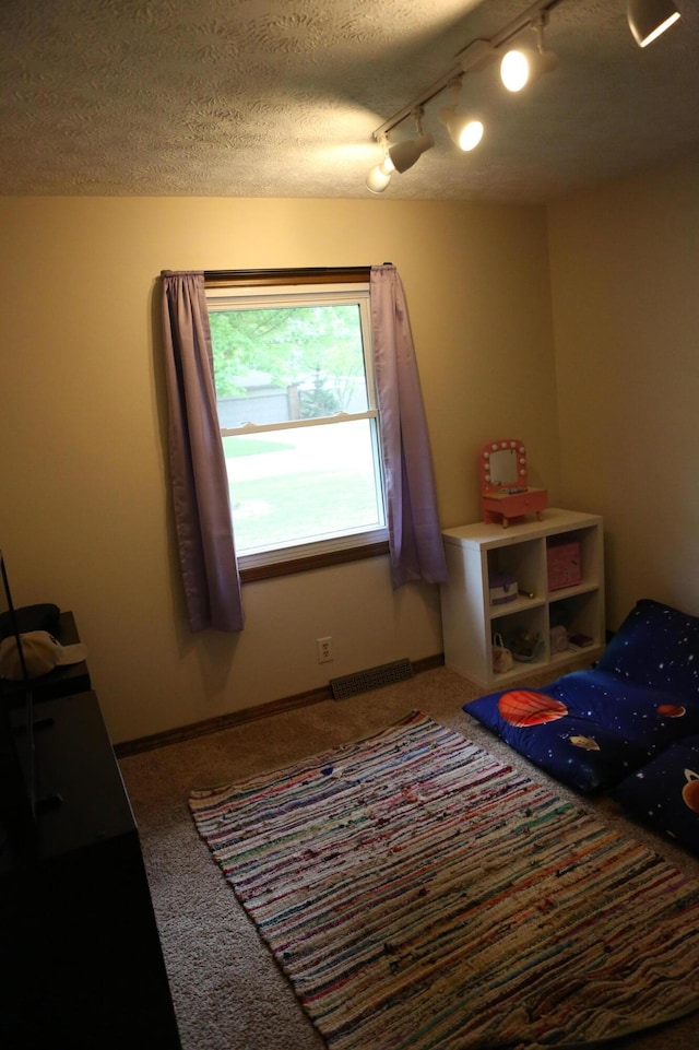carpeted bedroom with a textured ceiling, rail lighting, and ceiling fan