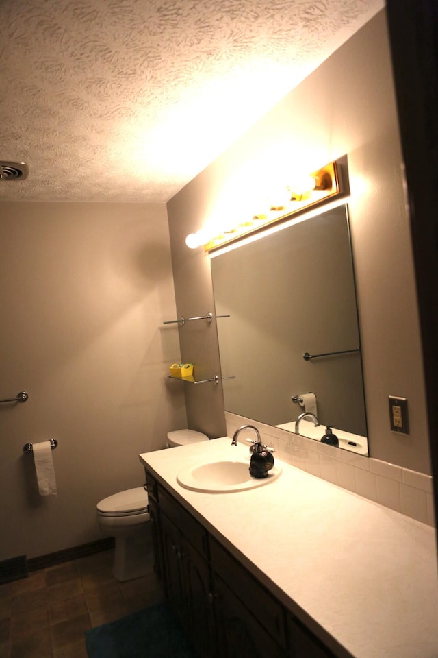 bathroom with a textured ceiling, toilet, and vanity