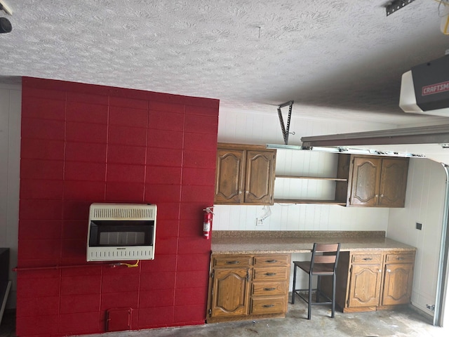 kitchen with heating unit, unfinished concrete flooring, a textured ceiling, and brown cabinetry