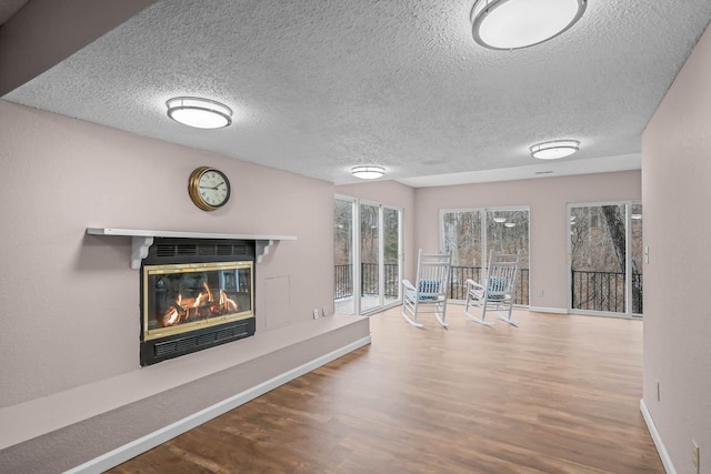 70 Roseville Dr, Rogersville, MO 65742 - unfurnished living room with a glass covered fireplace, wood finished floors, a textured ceiling, and baseboards
