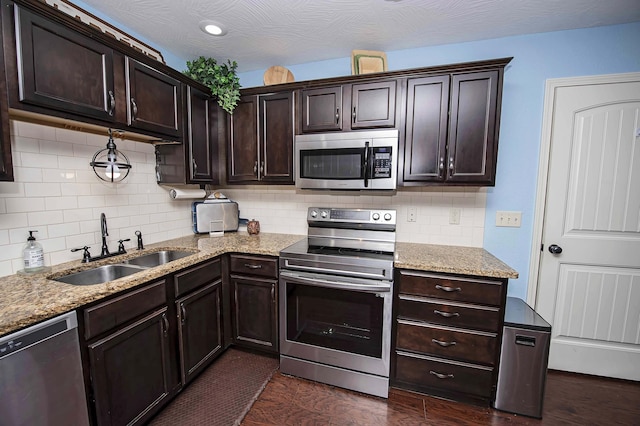 824 E Crystal Ave, Nixa, MO 65714 - kitchen featuring appliances with stainless steel finishes, a sink, dark brown cabinets, decorative backsplash, and light stone countertops