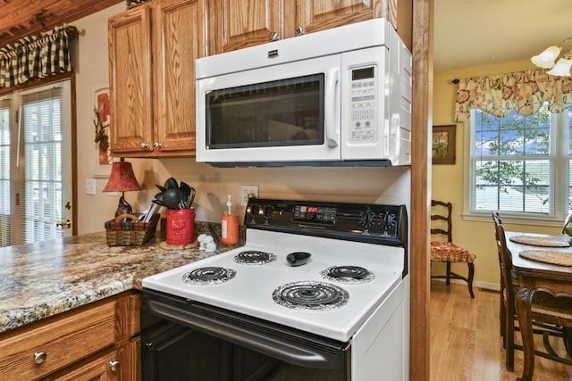 147 Liberty Ln, Kimberling City, MO 65686 - kitchen with electric range oven, white microwave, light wood-style flooring, brown cabinets, and baseboards