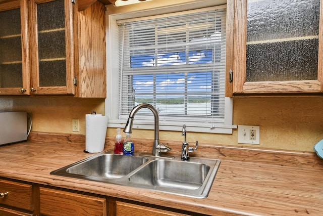 147 Liberty Ln, Kimberling City, MO 65686 - kitchen featuring a sink, glass insert cabinets, brown cabinetry, and wood counters