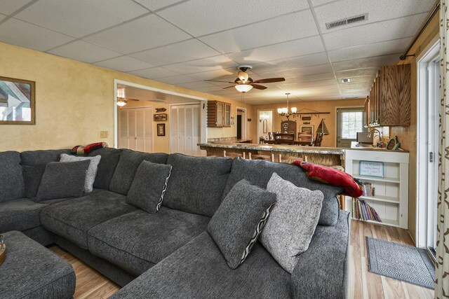 147 Liberty Ln, Kimberling City, MO 65686 - living area featuring a drop ceiling, light wood-type flooring, a ceiling fan, and a chandelier
