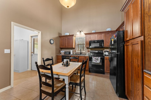 kitchen with black appliances, a high ceiling, light tile patterned floors, brown cabinets, and a sink