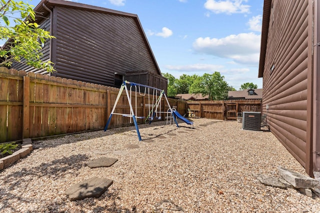 fenced backyard featuring a playground and central AC