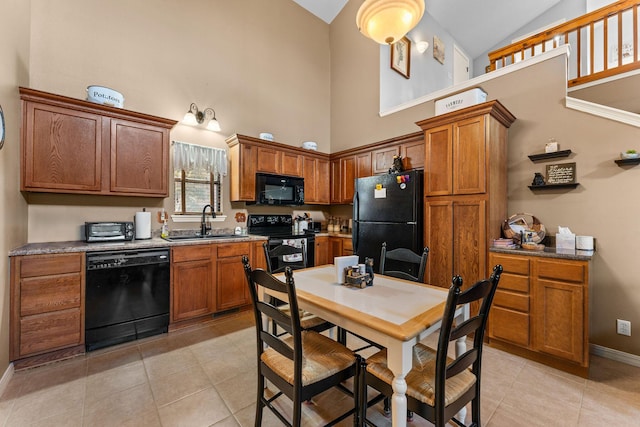 kitchen featuring black appliances, a sink, high vaulted ceiling, light tile patterned floors, and brown cabinets