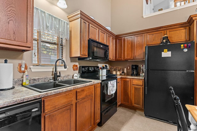 kitchen featuring black appliances, a sink, light countertops, light tile patterned floors, and brown cabinetry