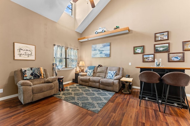 living area featuring high vaulted ceiling, wood finished floors, baseboards, healthy amount of natural light, and a ceiling fan