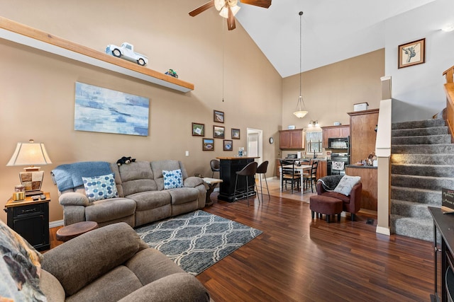 living room with a ceiling fan, high vaulted ceiling, dark wood-style flooring, stairway, and baseboards
