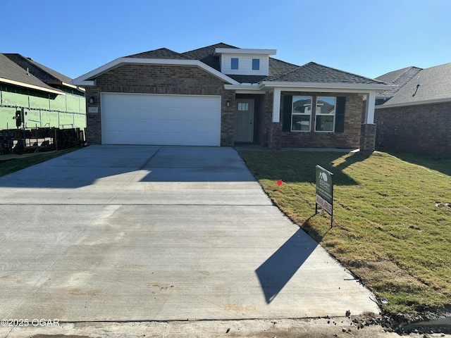 view of front of house featuring an attached garage, a front lawn, concrete driveway, and brick siding