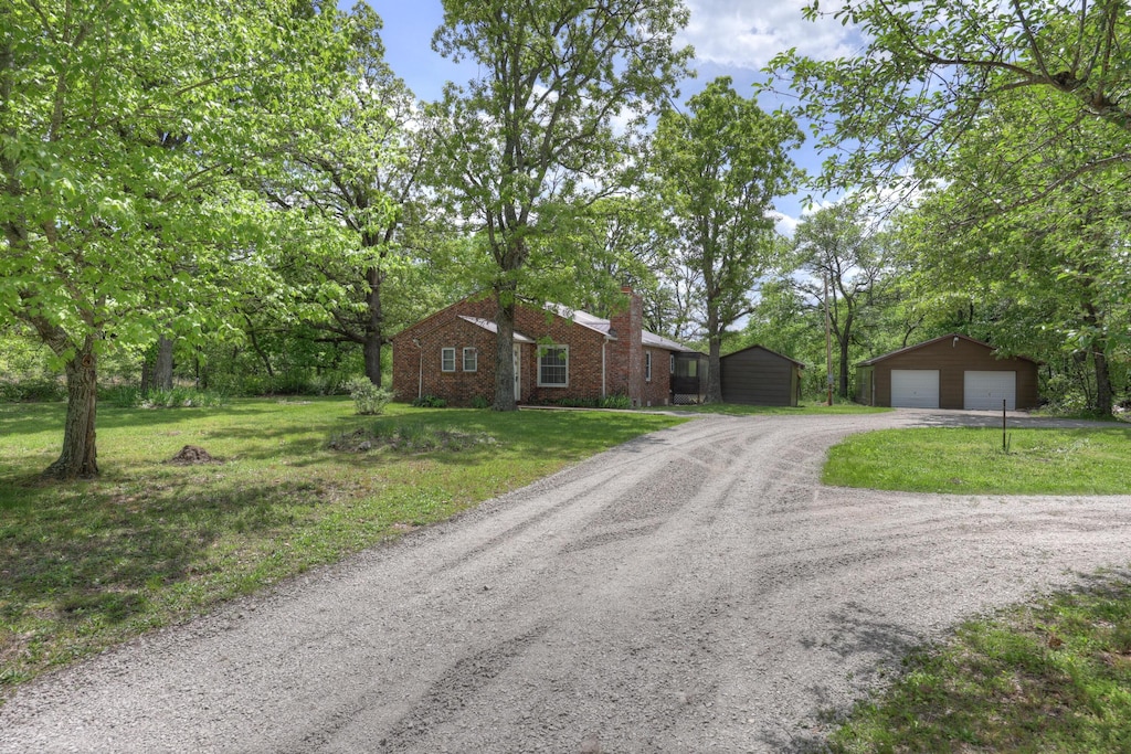 4095 Gum Rd, Seneca, MO 64865 - view of front of house with an outbuilding, a detached garage, a chimney, dirt driveway, and a front yard