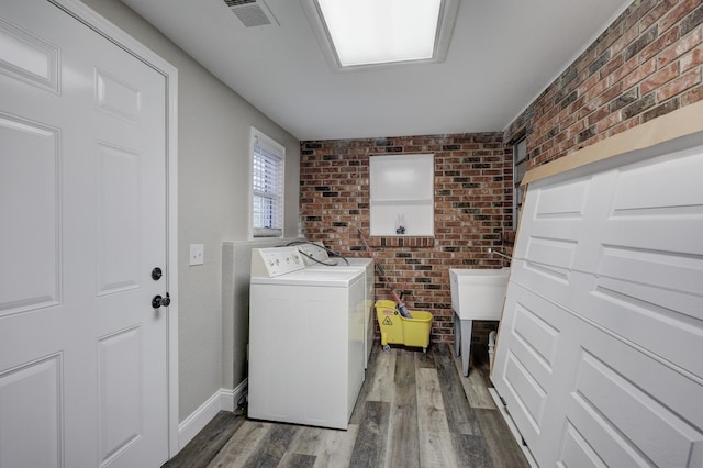 laundry room with brick wall, wood finished floors, and baseboards