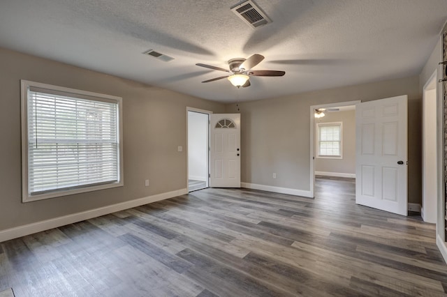 unfurnished room featuring ceiling fan, baseboards, dark wood-style floors, and a textured ceiling