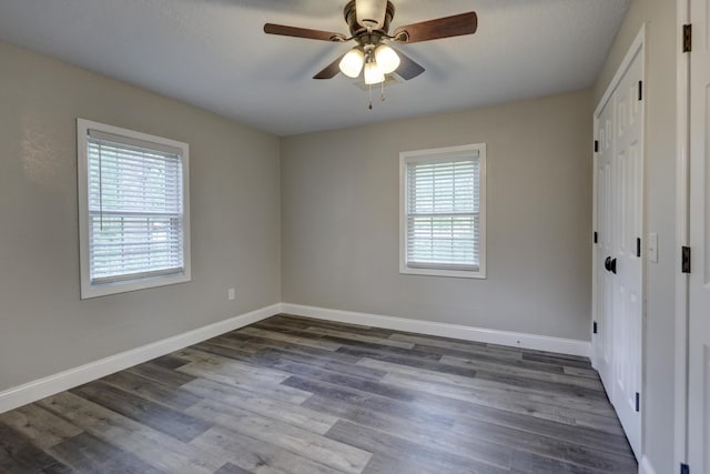 unfurnished bedroom featuring baseboards, dark wood finished floors, a closet, and a ceiling fan