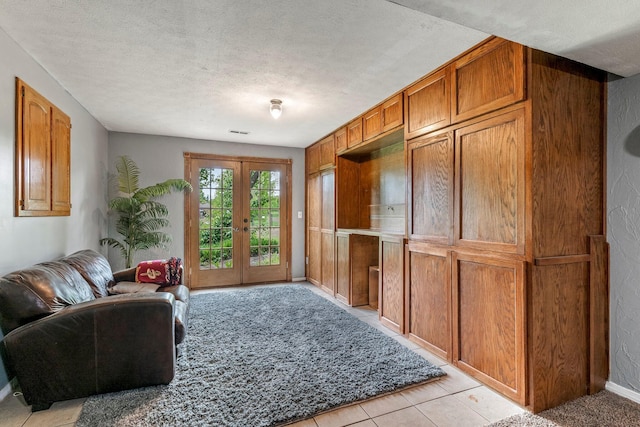 living area featuring french doors, a textured ceiling, and baseboards