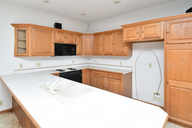 kitchen with black appliances, a sink, light countertops, and glass insert cabinets