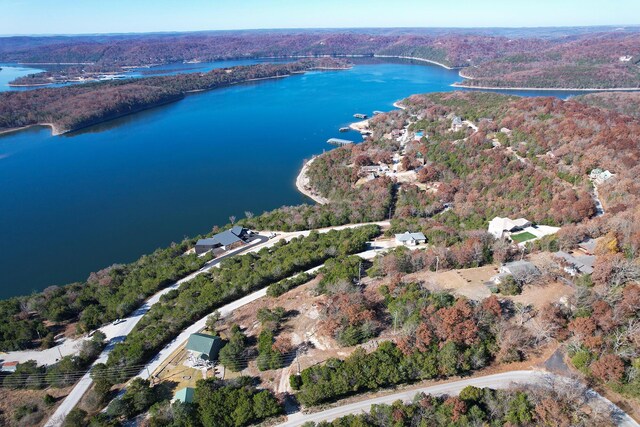 aerial view of property's location featuring a nearby body of water and a heavily wooded area