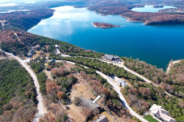 drone / aerial view of a nearby body of water and a heavily wooded area