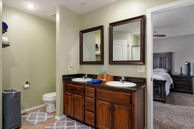 ensuite bathroom with double vanity, toilet, and baseboards