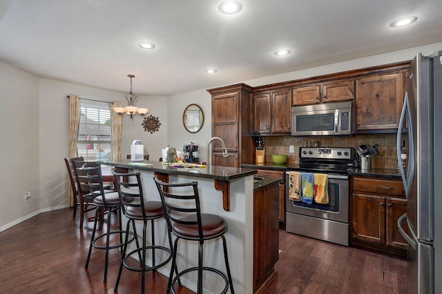 kitchen with stainless steel appliances, dark wood-style floors, tasteful backsplash, a chandelier, and recessed lighting
