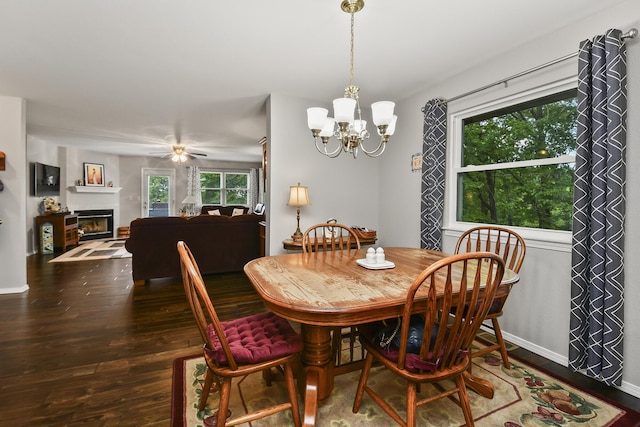 138 Canyon Forest Cir, Kimberling City, MO 65686 - dining area featuring wood finished floors, a chandelier, a glass covered fireplace, baseboards, and ceiling fan