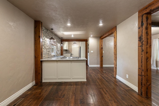 kitchen featuring dark wood-type flooring, white cabinetry, a peninsula, a sink, and recessed lighting