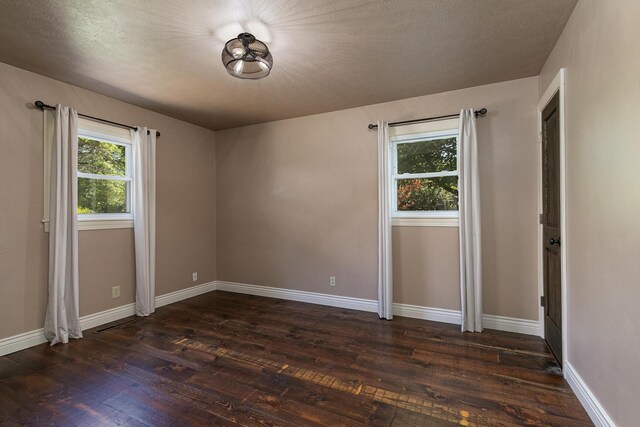 empty room featuring dark wood-style floors and baseboards