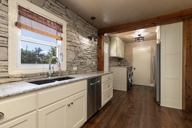 kitchen featuring appliances with stainless steel finishes, a sink, washer / clothes dryer, backsplash, and dark wood finished floors