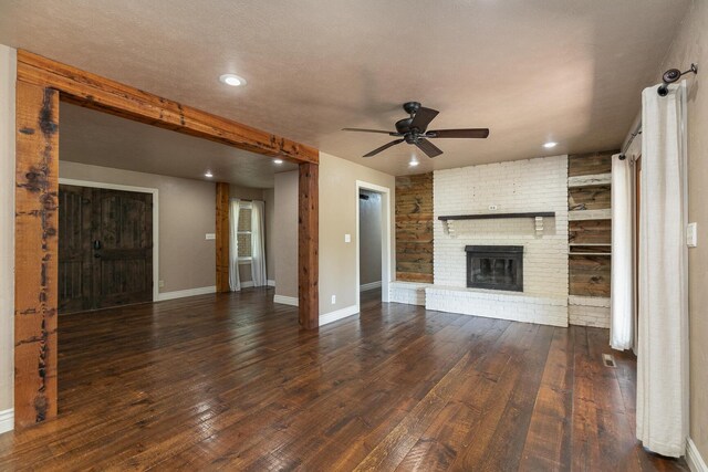 unfurnished living room with a ceiling fan, a brick fireplace, dark wood-type flooring, baseboards, and recessed lighting