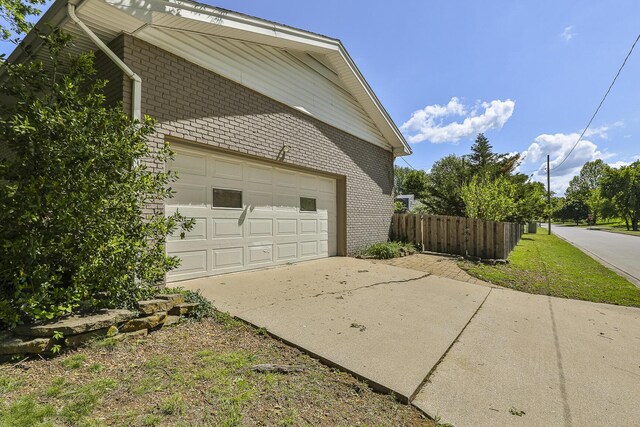 garage featuring concrete driveway and fence