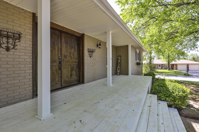 view of exterior entry with brick siding and covered porch