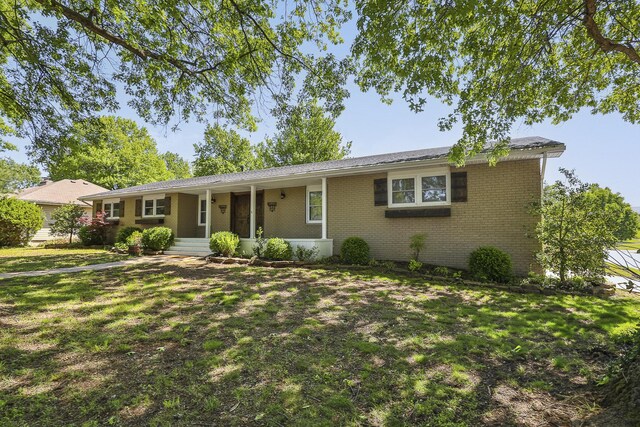 ranch-style house featuring brick siding, a front yard, and covered porch