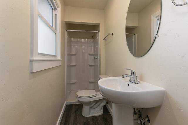 bathroom featuring wood finished floors, toilet, a shower, and baseboards
